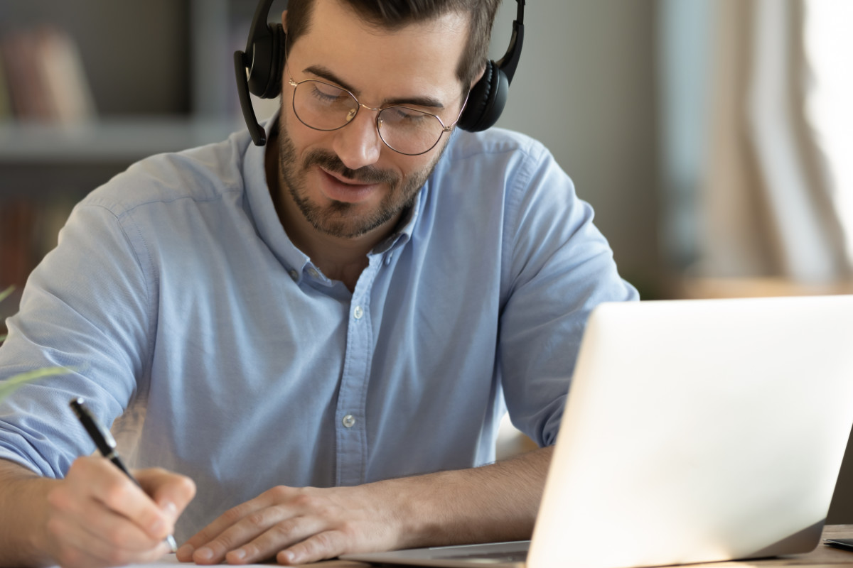 Man with headphones taking notes